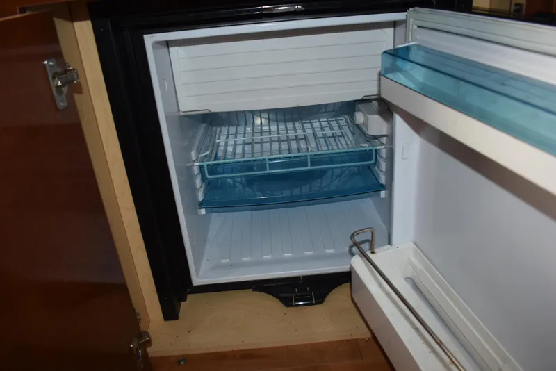 Slide: The Image of Open refrigerator inside a 2011 Sea Ray 310 Sundancer boat, showing empty shelves. - 46