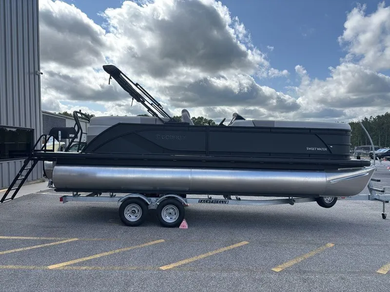 The Image of 2025 Godfrey SWEETWATER 2286 SB pontoon boat on trailer, parked outdoors. - 1