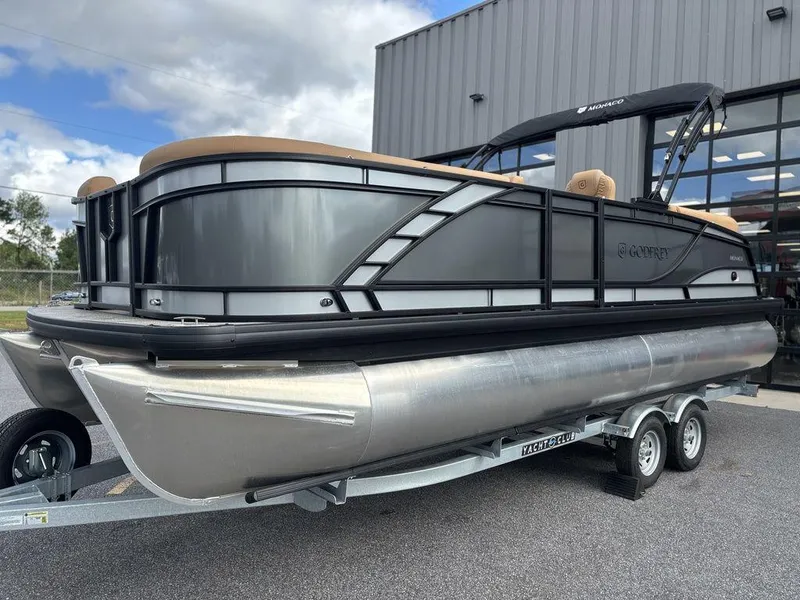 Slide: The Image of 2025 Godfrey Monaco 235 SB pontoon boat on trailer, parked outside a building. - 5