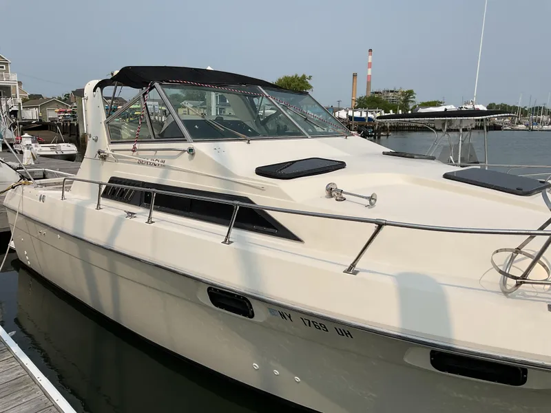 Slide: The Image of 1985 Cruisers Yachts 291 Sea Devil docked at marina, featuring sleek design and spacious deck. - 1