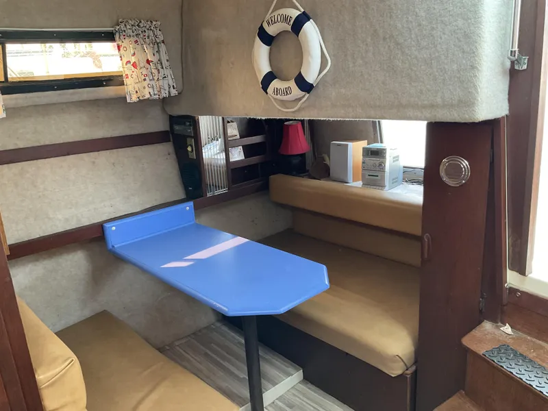 Slide: The Image of 1985 Cruisers Yachts 291 Sea Devil interior with blue table and beige seating. - 12