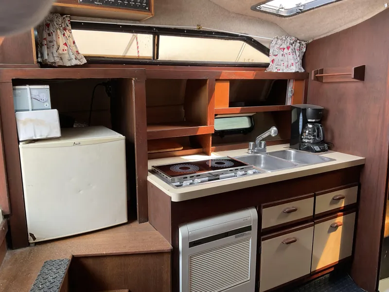Slide: The Image of 1985 Cruisers Yachts 291 Sea Devil interior kitchen with stove, sink, fridge, and coffee maker. - 14