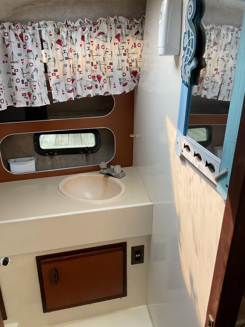 Slide: The Image of 1985 Cruisers Yachts 291 Sea Devil bathroom with sink, mirror, and nautical-themed curtains. - 20