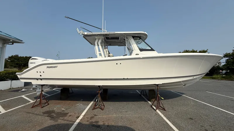 The Image of 2025 Pursuit S 328 Sport boat on stands in a parking lot. - 1