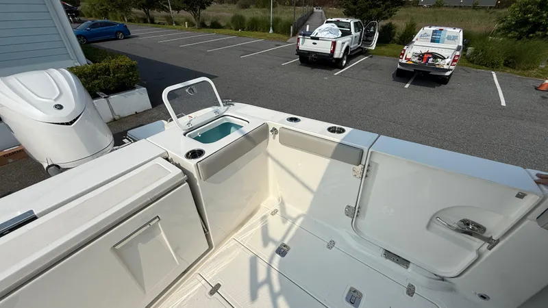 Slide: The Image of 2025 Pursuit S 328 Sport boat deck with storage and seating in a parking lot. - 16