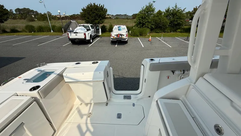 Slide: The Image of 2025 Pursuit S 328 Sport boat interior with parking lot view, featuring two parked vehicles. - 20