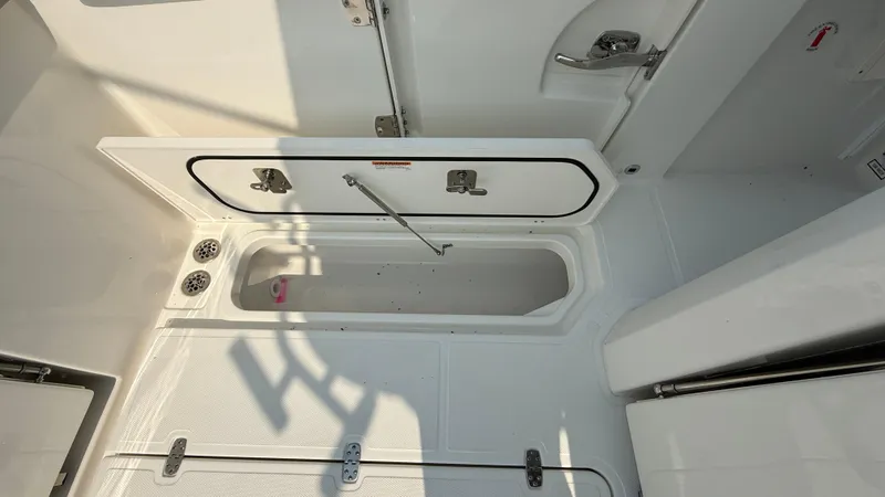 Slide: The Image of 2025 Pursuit S 328 Sport boat storage compartment, open hatch, white interior. - 24