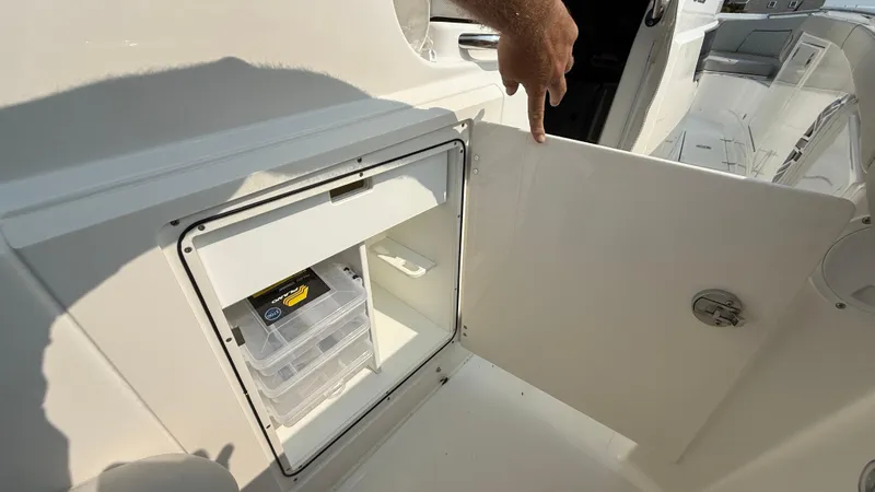 Slide: The Image of 2025 Pursuit S 328 Sport boat storage compartment with tackle box inside. - 36