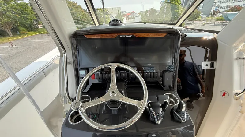 Slide: The Image of 2025 Pursuit S 328 Sport boat helm with steering wheel and control panel. - 41