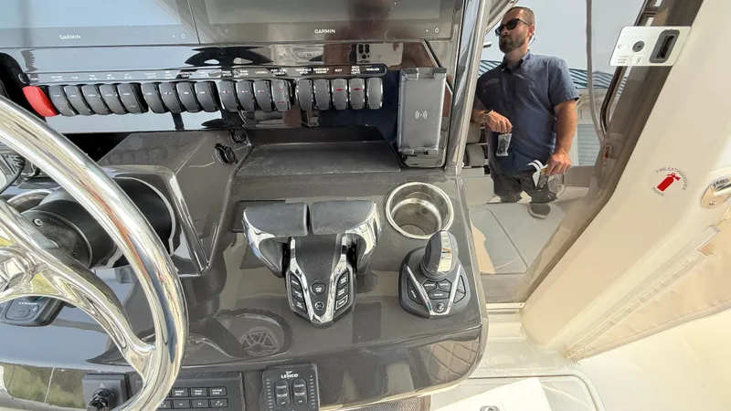 Slide: The Image of 2025 Pursuit S 328 Sport boat dashboard with controls and reflection of a person. - 44