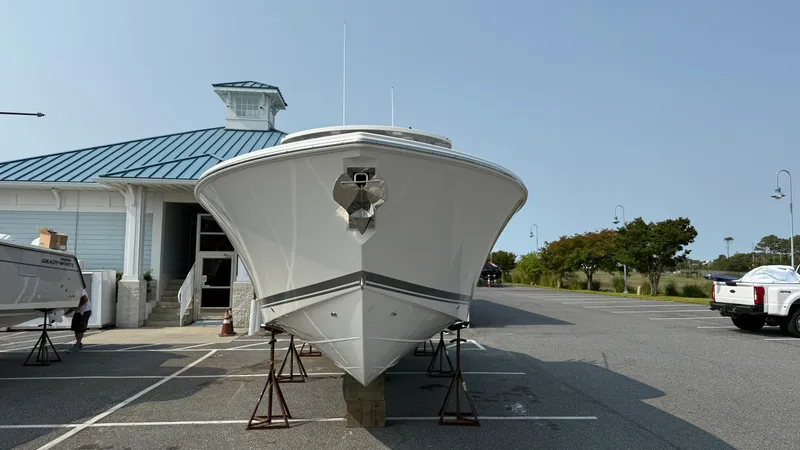 Slide: The Image of 2025 Pursuit S 328 Sport boat on stands in parking lot near building. - 8
