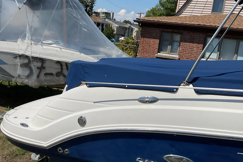 Slide: The Image of 2006 Chaparral 256 SSi boat with blue cover, parked near a brick house. - 10