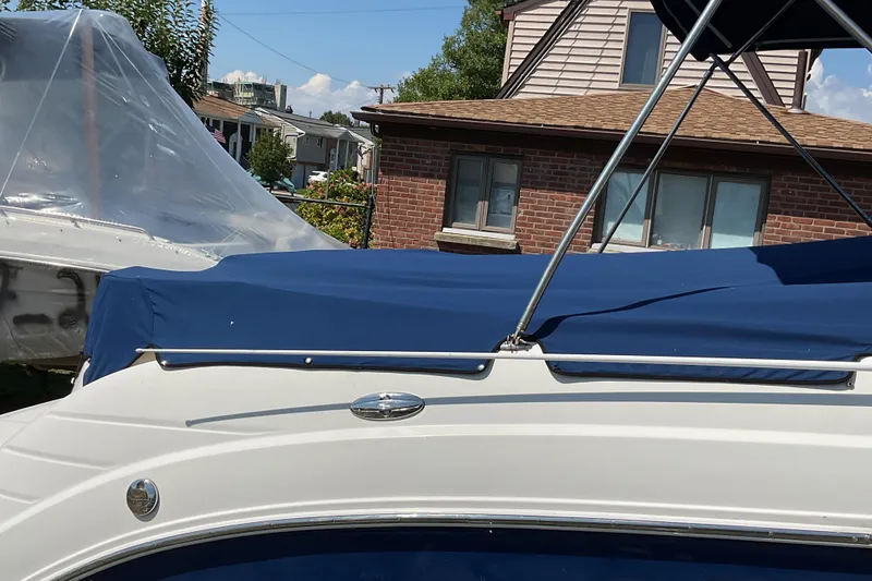 Slide: The Image of 2006 Chaparral 256 SSi boat with blue cover, parked near a brick house. - 9