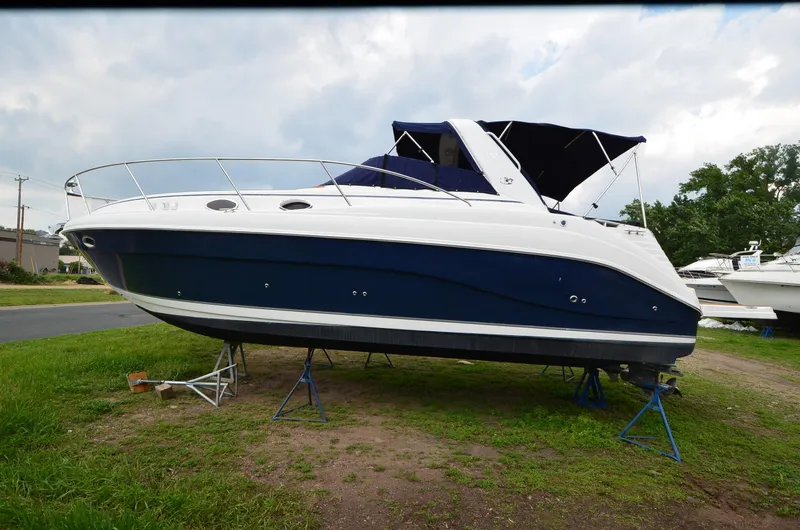 Slide: The Image of 2006 Rinker 342 Fiesta Vee boat on stands, blue and white exterior, parked on grass. - 14