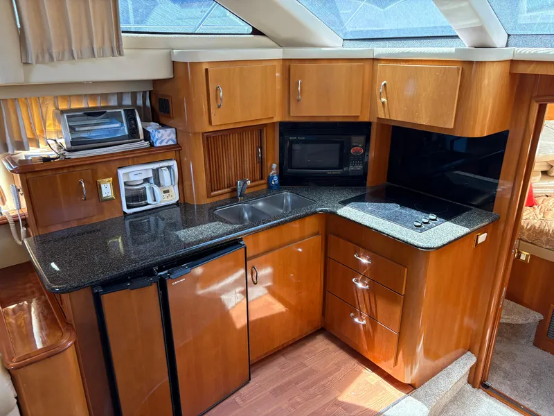 Slide: The Image of 2005 Carver 44 CPMY yacht kitchen with wood cabinets, black countertops, and modern appliances. - 17