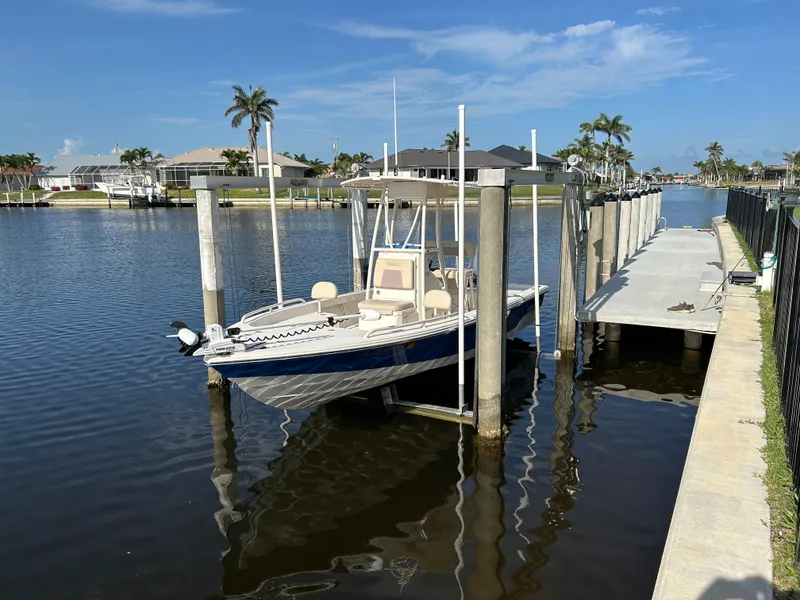 The Image of 2019 Pathfinder 2200 CC boat docked in a sunny canal with palm trees. - 0