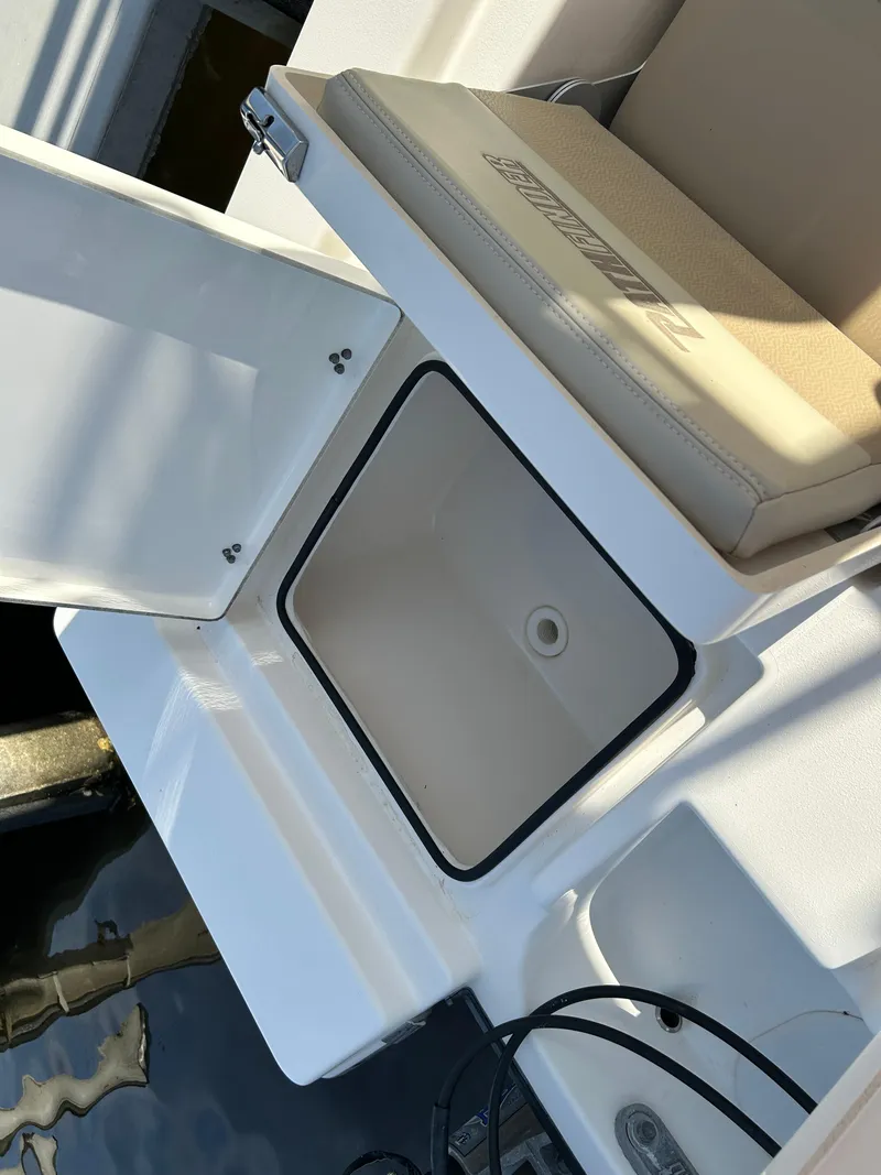 Slide: The Image of 2019 Pathfinder 2200 CC boat storage compartment with cushioned seat, open on a sunny day. - 22