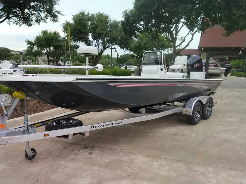 Slide: The Image of 2025 Ranger RB210 boat on trailer, parked outdoors with trees in the background. - 1