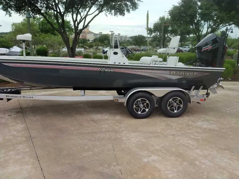 Slide: The Image of 2025 Ranger RB210 boat on trailer, parked outdoors with trees in background. - 5