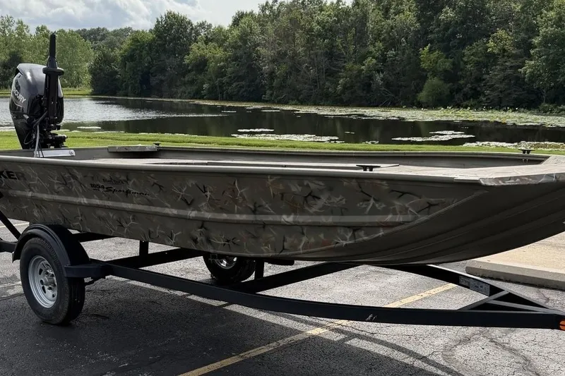 The Image of A 2025 Tracker Grizzly 1654 T Sportsman on a trailer by a serene lake. - 0