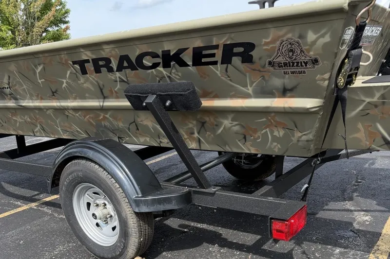 Slide: The Image of 2025 Tracker Grizzly 1654 T Sportsman boat on trailer, featuring camo design and sturdy build. - 3