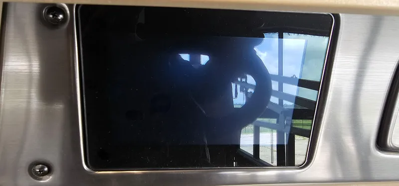 Slide: The Image of Dashboard screen of 2025 Sun Tracker Party Barge 18 DLX, reflecting steering wheel and outdoor view. - 10