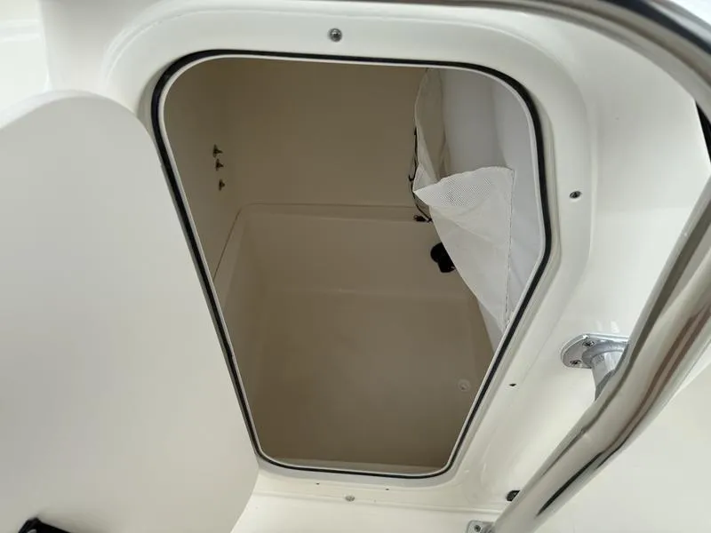 Slide: The Image of 2025 Bulls Bay 230 Center Console storage compartment, open door view, white interior. - 11