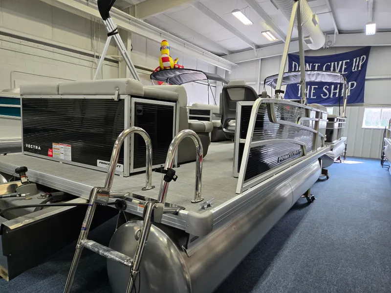 Slide: The Image of 2025 Princecraft Vectra 19 L pontoon boat displayed indoors with ladder and seating. - 2