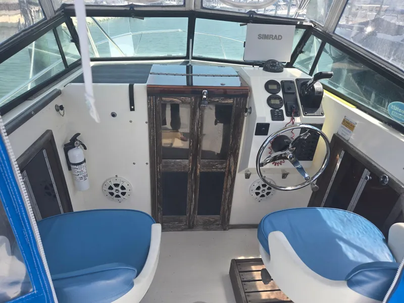 Slide: The Image of 1989 Parker 2310 Walkaround boat interior with steering wheel, blue seats, and navigation equipment. - 2