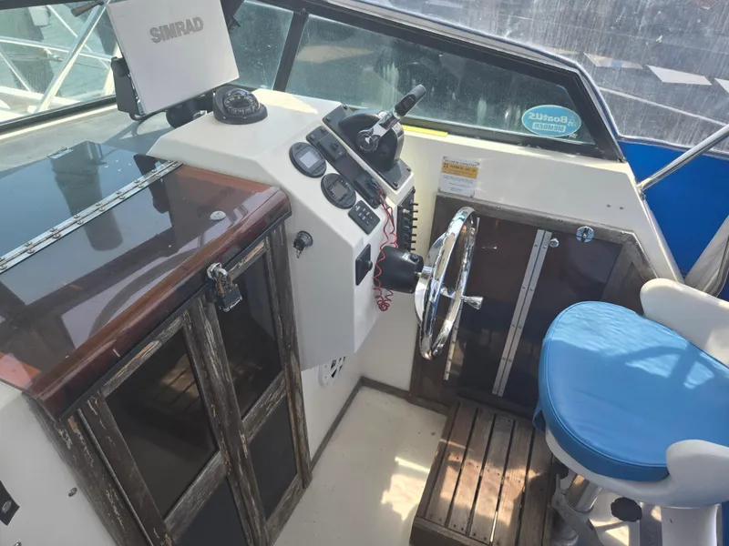 Slide: The Image of 1989 Parker 2310 Walkaround boat cockpit with steering wheel, gauges, and blue captain's chair. - 3