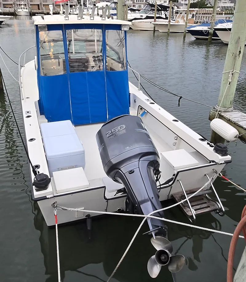 Slide: The Image of 1989 Parker 2310 Walkaround boat docked with outboard motor and blue canopy. - 5
