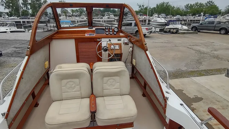 Slide: The Image of 1988 Shamrock 220 Predator boat interior with dual seats and wooden dashboard at a marina. - 7