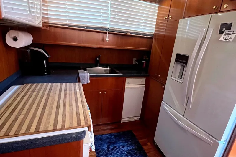 Slide: The Image of Compact kitchen in a 1999 Jefferson Marquessa 56 yacht with wood cabinetry and modern appliances. - 49