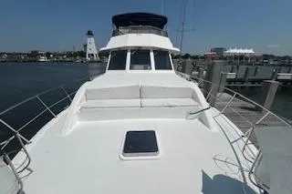 Slide: The Image of 1999 Jefferson Marquessa 56 yacht docked at marina, featuring spacious deck and clear sky. - 6