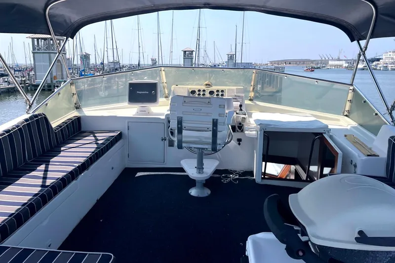 Slide: The Image of 1999 Jefferson Marquessa 56 yacht helm with striped seating, marina view, and navigation equipment. - 8