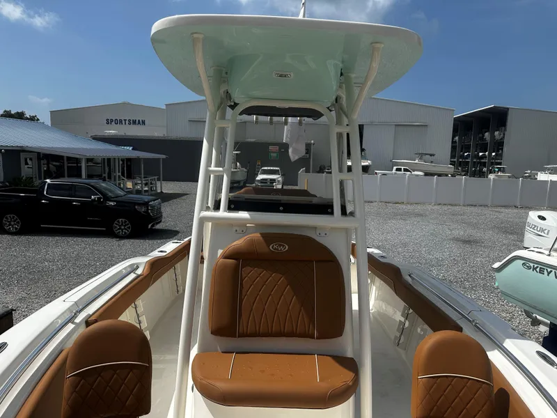 Slide: The Image of 2025 Key West 219fs boat with tan seating, parked outdoors near dealership. - 11