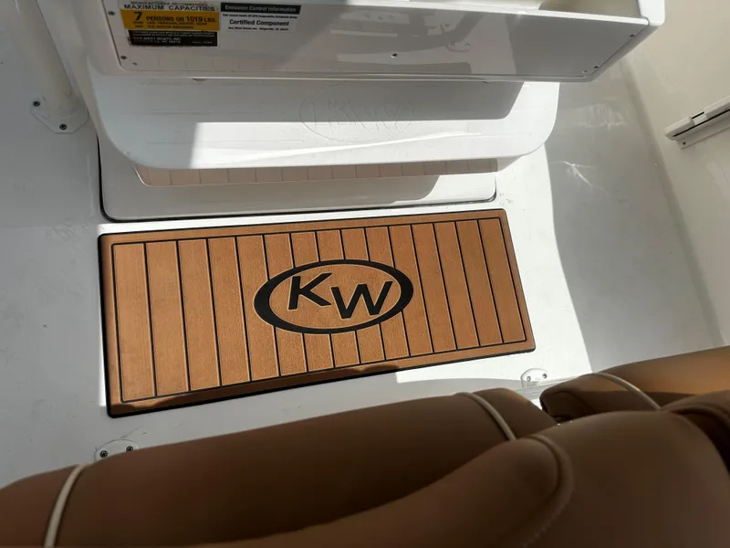Slide: The Image of Key West 219fs 2025 boat interior with KW logo mat and brown seating. - 7