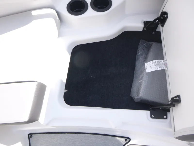 Slide: The Image of 2025 Yamaha Boats AR220 storage compartment with cup holders and cushioned seating. - 11