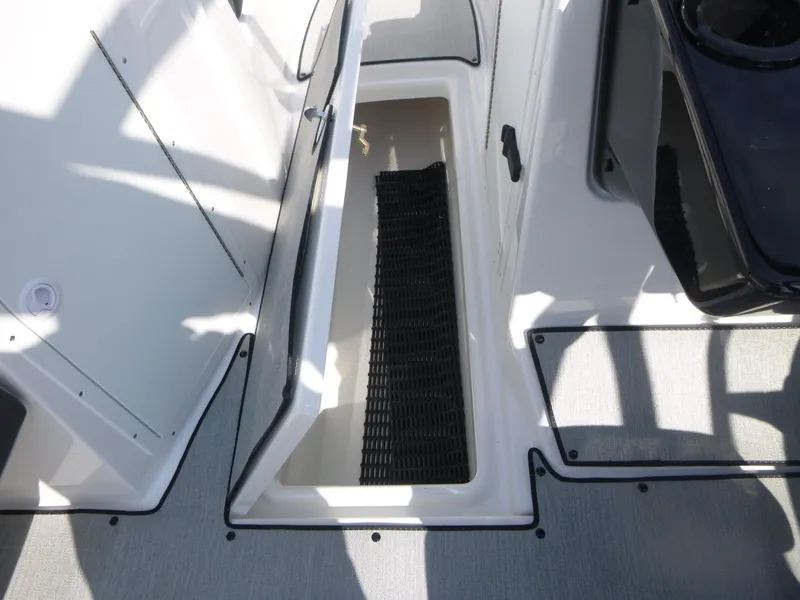 Slide: The Image of 2025 Yamaha Boats AR220 storage compartment with open hatch, showcasing interior space. - 12