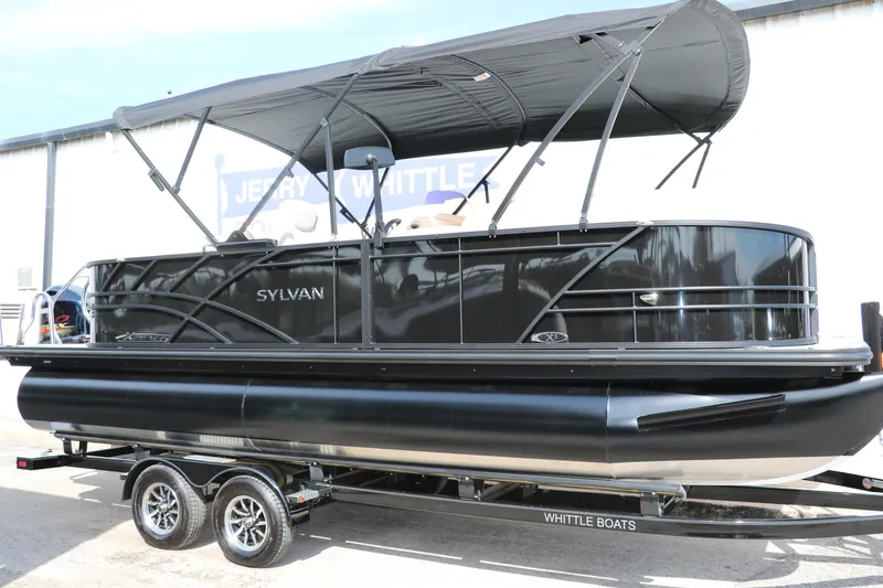 The Image of 2025 Sylvan Mirage X3 pontoon boat on trailer, featuring sleek black design and canopy. - 0