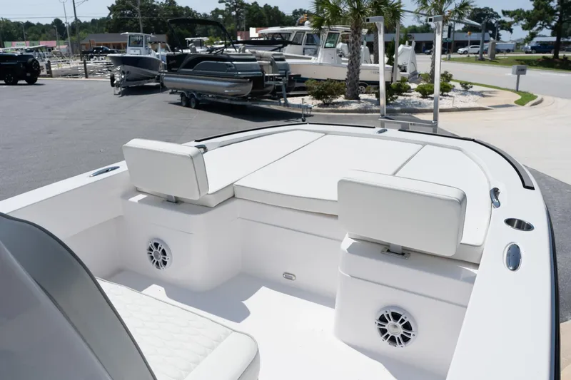 Slide: The Image of 2026 Twin Vee 22 Baycat boat interior with white seating and speakers, parked outdoors. - 21