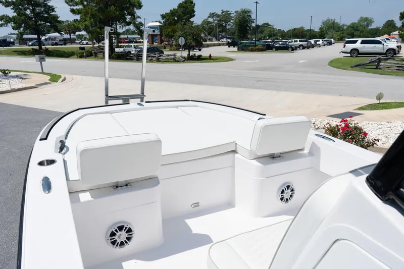 Slide: The Image of 2026 Twin Vee 22 Baycat boat interior with white seating and speakers, parked outdoors. - 24