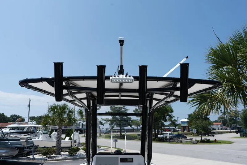 Slide: The Image of 2026 Twin Vee 22 Baycat boat with T-top and rod holders, parked outdoors. - 26