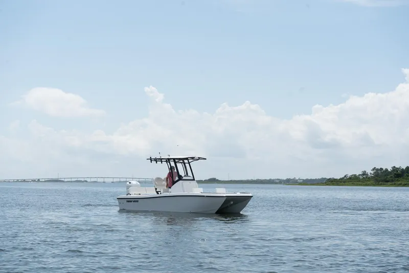 Slide: The Image of 2026 Twin Vee 22 Baycat boat on calm water under a clear sky. - 3