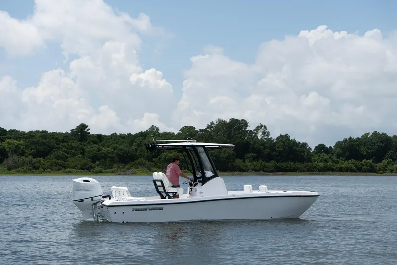 Slide: The Image of 2026 Twin Vee 22 Baycat boat on calm water, with lush green shoreline in background. - 4