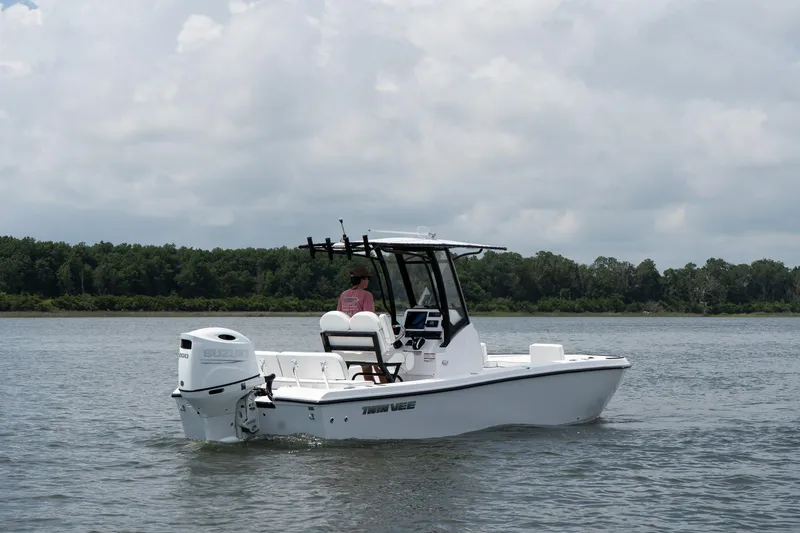 Slide: The Image of 2026 Twin Vee 22 Baycat boat on calm water, overcast sky, lush green shoreline. - 6