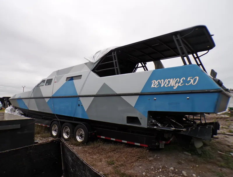 Slide: The Image of Custom Revenge 50 boat from 2001 on a trailer, featuring a geometric blue and gray design. - 1