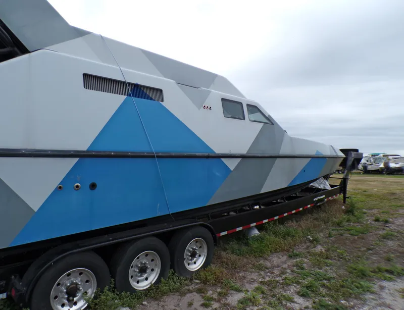 Slide: The Image of Custom Revenge 50 boat, 2001 model, on trailer with geometric design, parked on grass. - 2