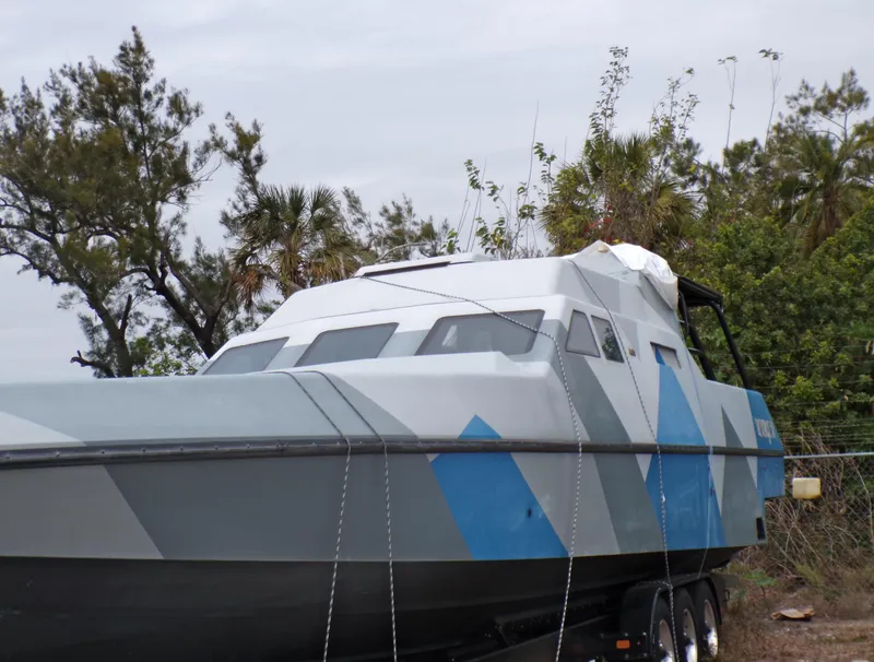 Slide: The Image of Custom Revenge 50 boat, 2001 model, on trailer with geometric design, surrounded by trees. - 26