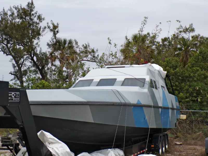 Slide: The Image of Custom Revenge 50 boat from 2001 on trailer, surrounded by trees. - 27